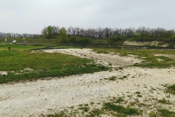 Terrain sableux avec des tuyaux au sol et des arbres en arrière-plan